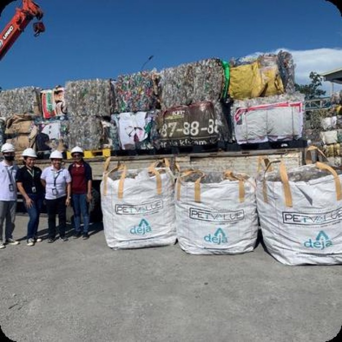 Staff in hard hats beside bales of recyclables and large PETValue bulk bags ready to move to a recycler